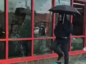 The mysterious 'Umbrella Man' is seen smashing windows.
