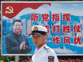 A member of the Chinese navy stands in front of a billboard showing Chinese President Xi Jinping photographed against a backdrop of Hong Kong, at China's Stonecutters Island naval base in Hong Kong, in a file photo from June 30, 2019.