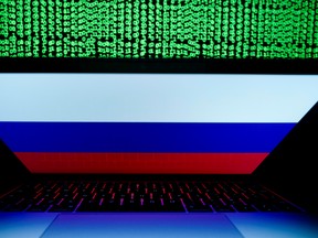 A Russian flag is seen on the laptop screen in front of a computer screen on which cyber code is displayed, in this illustration picture taken March 2, 2018.