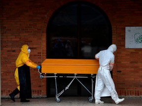 Workers move the coffin of a COVID-19 victim to be cremated at Serafin cemetery in Bogota, on July 4, 2020.