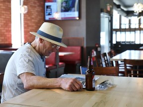 Dave Prine enjoys a cold beer inside an otherwise empty restaurant in downtown Kitchener, Ont., on Friday, July 17, 2020. Eat-in dining was being allowed as much of Ontario moved to Stage 3 of its COVID reopening plan.