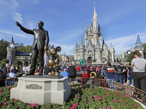 In this Jan. 9, 2019 photo, guests watch a show near a statue of Walt Disney and Micky Mouse in front of the Cinderella Castle at the Magic Kingdom at Walt Disney World in Lake Buena Vista, part of the Orlando area in Fla.