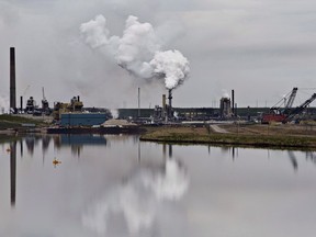 An oil sands extraction facility is reflected in a tailings pond near the city of Fort McMurray, Alberta on Sunday June 1, 2014. Alberta suspended environmental monitoring for oilsands companies without notifying the Northwest Territories, despite a legally binding agreement promising to do so.