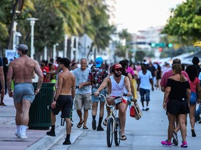 A cyclist negotiates the throngs on Ocean Drive in Miami Beach, Florida on June 26, 2020.