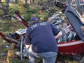 Members of the Transportation Safety Board of Canada have completed their work at the scene of a fatal helicopter crash in Newfoundland and Labrador. A TSB investigator examines wreckage of a Robinson R44 helicopter which crashed near Thorburn Lake, N.L., in an undated handout photo. One man was killed and two others sent to hospital as a result of the crash.