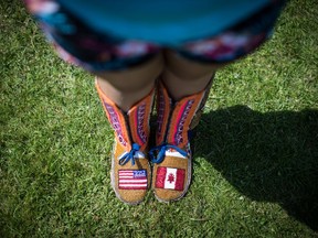 Red Moon Roberts, 16, from the Sto:lo Nation near Chilliwack, B.C., wears moccasins bearing the flags of the United States and Canada crafted from beads as she poses for a photograph before competing during the final day of the 32nd annual Squamish Nation Youth Powwow, in West Vancouver, B.C., on Sunday July 14, 2019.