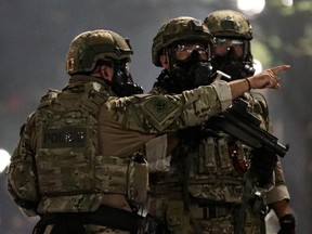 A federal law enforcement official points to demonstrators before firing tear gas during a protest against racial inequality in Portland, Oregon, U.S., July 19, 2020.