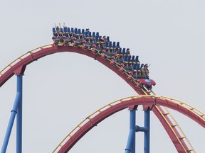 People wear face masks as they ride 'The Goliath', roller coaster at La Ronde amusement park in Montreal, Saturday, July 25, 2020, as the COVID-19 pandemic continues in Canada and around the world. The wearing of masks or protective face coverings was mandatory in Quebec as of July 18.