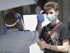 A man has temperature checked before entering a store in Montreal, Saturday, July 25, 2020, as the COVID-19 pandemic continues in Canada and around the world.