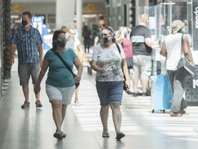People wear face masks as they walk through a shopping mall in Montreal, Saturday, July 18, 2020, as the COVID-19 pandemic continues in Canada and around the world. The wearing of masks or protective face coverings is mandatory in Quebec as of today.