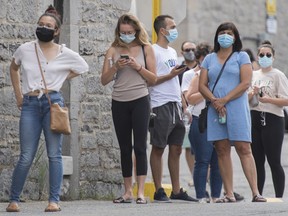 People wait to be tested for COVID-19 at a testing clinic in Montreal, Sunday, July 12, 2020, as the COVID-19 pandemic continues in Canada and around the world. Quebec plans to make masks mandatory in all public indoor spaces across the province this week, several media outlets are reporting.