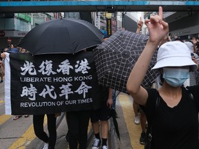 Protesters hold a flag reading "Liberate Hong Kong, Revolution of Our Times" during a protest in Hong Kong, China, on Wednesday, July 1, 2020.