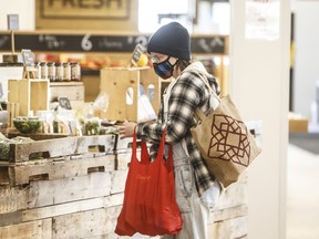 A shopper wearing a mask buys groceries at a sparse farmers market in Edmonton on Sunday March 22, 2020. Edmonton city council voted 10-3 Wednesday afternoon to make masks mandatory in all public indoor spaces starting Aug. 1. Councillors Jon Dziadyk, Tony Caterina and Mike Nickel opposed the bylaw, which is an expansion of an emergency advisory committee decision to make face coverings mandatory in city facilities and on public transit, which was also set to begin next month.