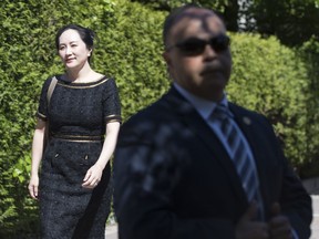 A security guard looks on as Meng Wanzhou, chief financial officer of Huawei, leaves her home to go to B.C. Supreme Court in Vancouver, Wednesday, May 27, 2020. The federal government is trying to block Huawei executive Meng Wanzhou's access to some documents in her extradition case, arguing in court documents that disclosing sensitive information would harm national security.