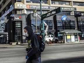 A pedestrian wearing a mask walks down the empty streets of downtown Edmonton on Sunday March 22, 2020. The Alberta government is giving out 20 million more face masks to help stem the spread of COVID-19, but Premier Jason Kenney says it's not necessary to make face-covering mandatory.