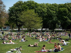 People sit and lie in the sun at Kitsilano Beach Park in Vancouver, on Saturday, May 9, 2020. As bars, restaurants and house parties continue to play significant roles in spreading COVID-19, some infectious disease experts in Canada think it's time to offer a safer alternative to drinking in public.