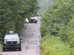 Police officers search a back road on Saturday, July 11, 2020 in Saint-Apollinaire, Que. Quebec provincial police say the father of two young girls found dead over the weekend in a rural area southwest of Quebec City may be desperate and looking for materials to ensure his survival.THE CANADIAN PRESS/Jacques Boissinot