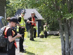 Police officers and volunteers stand in line before entering the woods to search, Friday, July 10, 2020 in Saint-Apollinaire Que. Police are continuing their search around a Quebec City suburb after they issued an Amber Alert Thursday for two young girls and their 44-year-old father who investigators believe disappeared following a highway car crash.THE CANADIAN PRESS/Jacques Boissinot