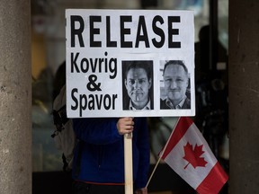 A man holds a sign bearing photographs of Canadians Michael Kovrig and Michael Spavor, who have been detained in China, outside B.C. Supreme Court in Jan. 2020. Spavor has since been sentence to 11 years for espionage.