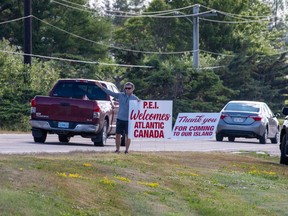 CP-Web.  Terry McKenna, a Charlottetown businessman representing a group of 25 business people, welcomes visitors to the province near Borden-Carleton, P.E.I., Friday, July 7, 2020.