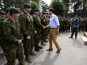 Prime Minister Justin Trudeau shakes hands with Canadian troops after delivering a speech at the Adazi Military Base in Kadaga, Latvia, on July 10, 2018. Canadian troops are being forced to hitch a ride with the British military to get to and from Latvia due to a shortage of working planes.