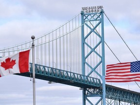 Canadian and American flags fly near the Ambassador Bridge at the Canada-USA border crossing in Windsor, Ont. on Saturday, March 21, 2020. The federal government appears to have relaxed restrictions at the Canada-U.S. border that would have made it impossible for first-year university students from the United States to enter the country.