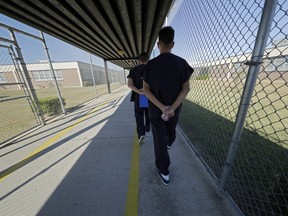 In a Thursday, Sept. 26, 2019 file photo, detainees walk with their hands clasped behind their backs along a line painted on a walkway inside the Winn Correctional Center in Winnfield, La. A proposed class-action lawsuit alleges authorities illegally strip searched federal prison inmates hundreds of thousands of times over almost three decades.