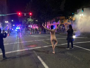'Naked Athena' performs a tree post infront of anti-riot police during a protest in Portland on Saturday night.