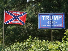 A campaign sign for U.S. President Donald Trump sits beside a Confederate flag bearing the words "I ain't coming down" in the backyard of a home in Sandston, Virginia, U.S., July 4, 2020.