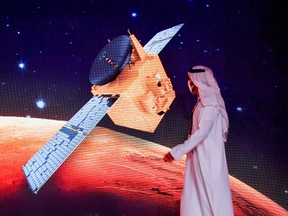 An Emirati walks past a screen displaying the "Hope" Mars probe at the Mohammed Bin Rashid Space Centre in Dubai on July 19, 2020, ahead of it's expected launch from Japan.