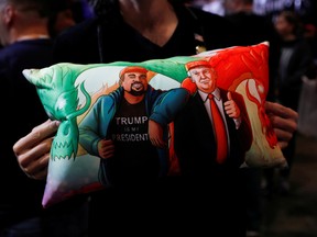 A supporter of U.S. President Donald Trump holds a pillow of him and Kanye West at his campaign rally