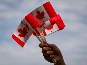 A volunteer hands out flags in a file photo from Canada Day festivities in Vancouver on July 1, 2013.