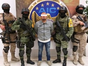 Members of the federal forces flank Jose Antonio Yepez, known as "El Marro," boss of the Santa Rosa de Lima cartel, after being captured early Sunday in the Franco Tavera village, in Guanajuato, Mexico August 2, 2020.
