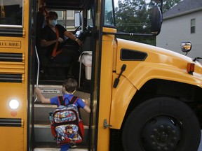 Paul Adamus, 7, climbs the stairs of a bus before the fist day of school on Monday, Aug. 3, 2020, in Dallas, Ga. Adamus is among tens of thousands of students in Georgia and across the nation who were set to resume in-person school Monday for the first time since March.