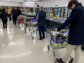 Shoppers shop at a supermarket in the suburb of Johnsonville in Wellington on August 11, 2020. - Auckland has been place at level 3 lockdown and the rest of the country has moved to level 2 after a family in South Auckland tested positive for COVID-19.