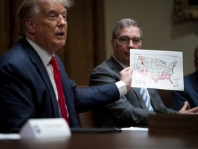 U.S. President Donald Trump holds up a map showing the coronavirus outbreak during a meeting in the Cabinet Room of the White House on August 3, 2020 in Washington, DC.