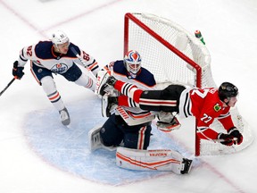 Kirby Dach of the Chicago Blackhawks gets tripped up against Mikko Koskinen and Caleb Jones of the Edmonton Oilers during the second period in Game 3 of the Western Conference Qualification Round prior to the 2020 NHL Stanley Cup Playoffs at Rogers Place in Edmonton on Aug. 5.