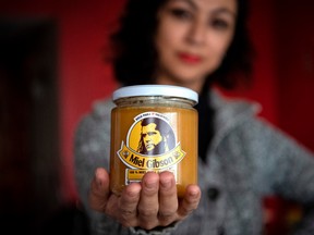 Chilean unemployed teacher Yohana Agurto, shows a jar of 'Miel Gibson' organic honey, at her home in Santiago, on August 18, 2020.
