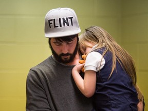Matt Hopper holds and comforts Nyla Hopper, age 5 of Flint, after she has her blood drawn to be tested for lead on January 26, 2016 at Eisenhower Elementary School in Flint, Michigan, following the city's water contamination and federal state of emergency.