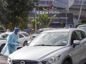 A health worker speaks with a motorist at a COVID-19 testing station setup at Eden Park, National Sports Stadium, in Auckland on August 14, 2020.