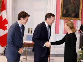 Bill Morneau, centre, shakes hands with Gov. Gen. Julie Payette, right, next to Prime Minister Justin Trudeau, at Rideau Hall in Ottawa, in 2019.