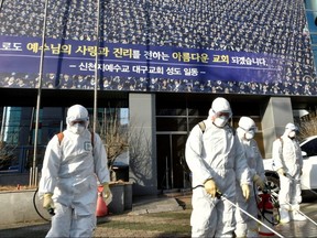 Workers from a disinfection service company sanitize a street in front of a branch of the Shincheonji Church of Jesus, the Temple of the Tabernacle of the Testimony, in Daegu, South Korea.