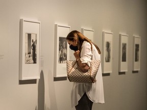 A patron wearing a mask looks closely at photographic work by Diane Arbus at Toronto's Art Gallery Of Ontario, August 20, 2020.