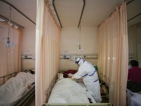 A medical staff member treats a patient infected by the COVID-19 coronavirus at Red Cross Hospital in Wuhan in China's central Hubei province on March 11, 2020.