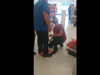 Screenshot from YouTube video shows a staff member at Shoppers Drug Mart standing atop a floor sign to stop man from peeling it off