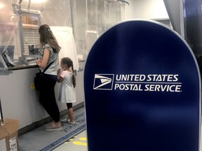 A woman and child do business at the counter in a United States Post Office