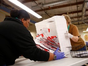 Workers empty a carton of ballots from a drop box to prepare them for the mail sorting machine during the presidential primary at King County Elections ballot processing center in Renton, Washington, U.S. March 10, 2020.