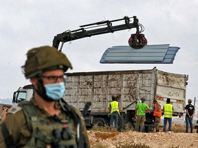 Israeli soldiers and border police gather as a structure serving as a home to a Palestinian family is demolished in the village of Susya south Yatta in the southern West Bank on August 11, 2020.