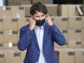 Prime Minister Justin Trudeau removes a cloth mask as he approaches the podium during an announcement at a factory in Brockville, Ont., Friday, Aug. 21, 2020.