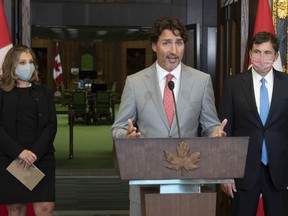 Standing in front of the House of Commons chamber Deputy Prime Minister and Minister of Finance Chrystia Freeland and President of the Queen's Privy Council for Canada and Minister of Intergovernmental Affairs Dominic LeBlanc look on as Prime Minister Justin Trudeau speaks during a news conference on parliament hill in Ottawa, Tuesday, Aug. 18, 2020.